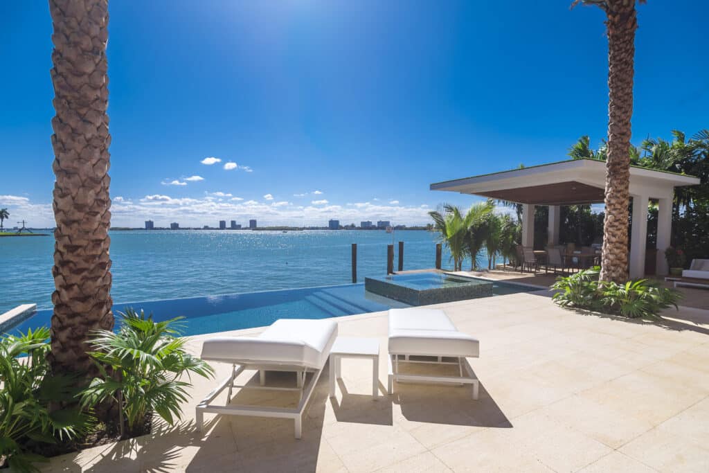 A pair of sunbathing chairs and an infinity pool at a luxurious home. Typical South Florida design.